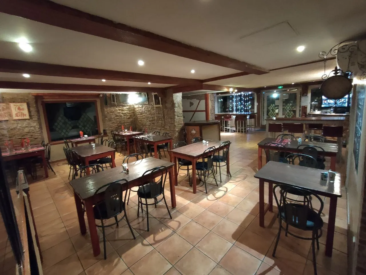 Salle du restaurant Mont Relais Gaillard avec tables en bois, murs en pierre et poutres apparentes.