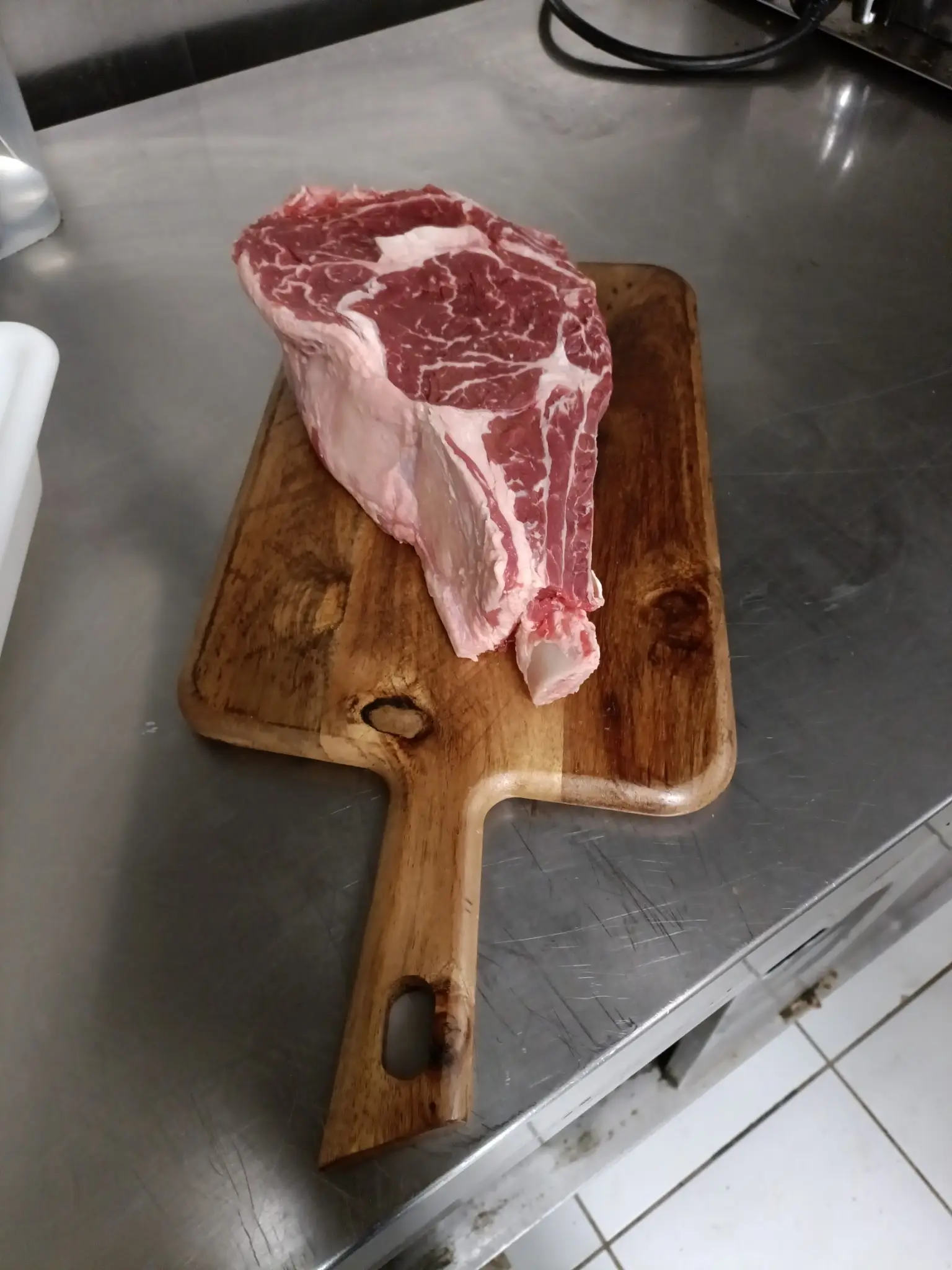 Épaisse pièce de bœuf crue sur une planche en bois dans la cuisine du restaurant.